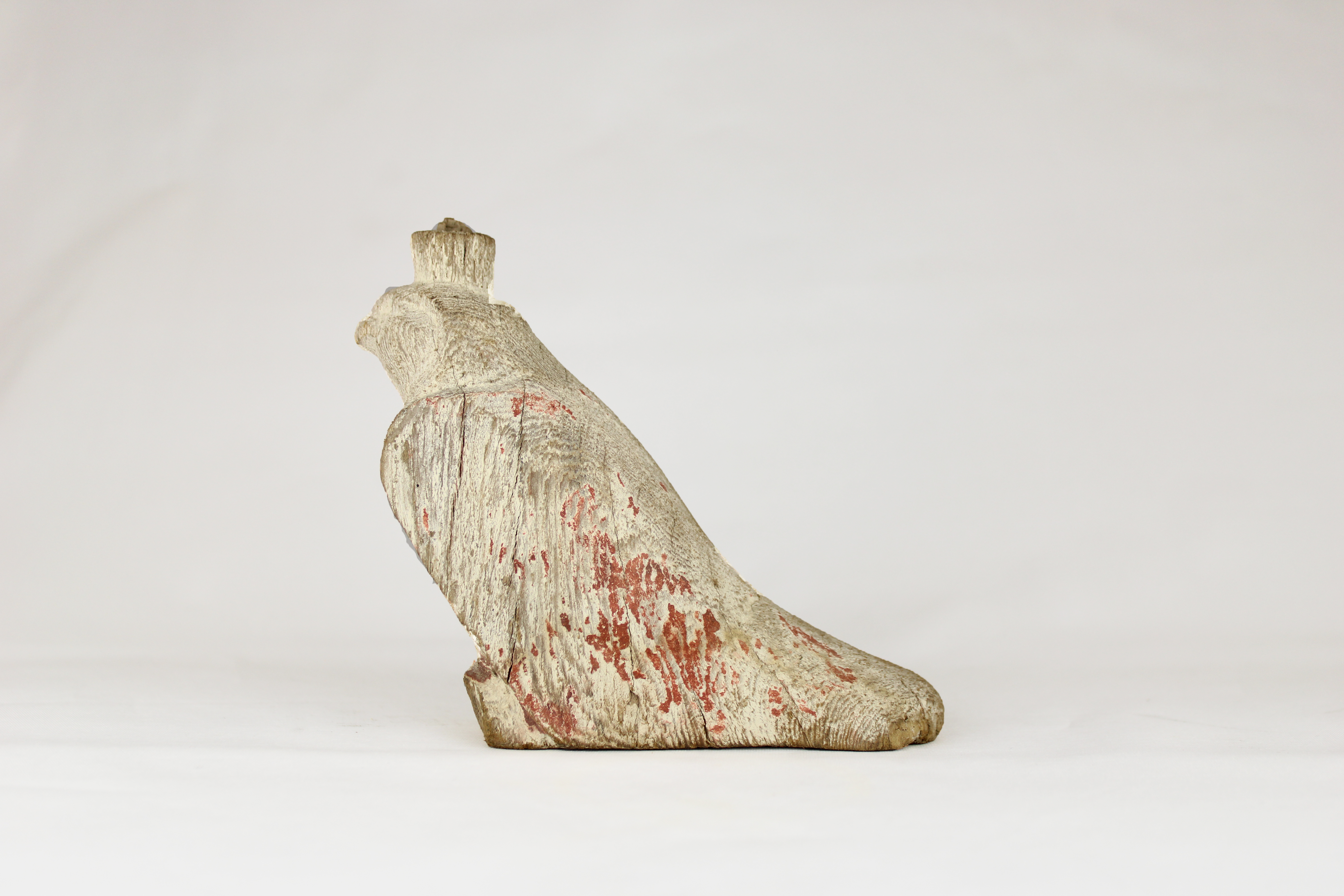 Image of a wooden figurine of a falcon, Egyptian, dating to between 2000 and 1500 BCE. Traces of reddish paint can be seen, especially on the lower portion of the body.