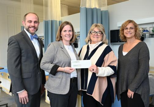 Four people holding a donation check