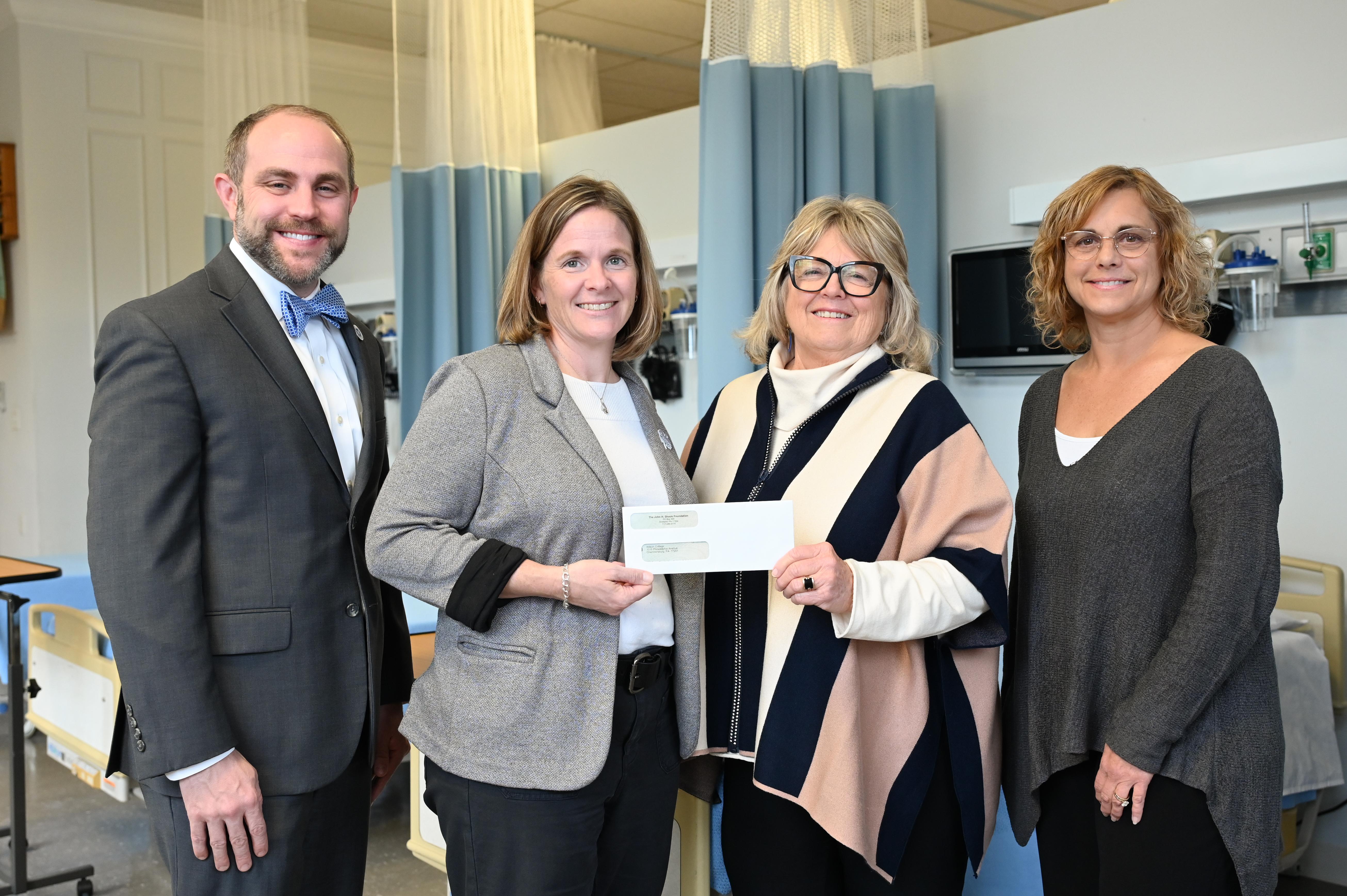 Four people holding a donation check